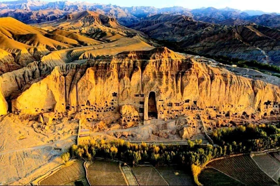 نمای هوایی دره بامیان با دیوارهٔ صخرهای طاقچههای بودا هنگام غروب آفتاب